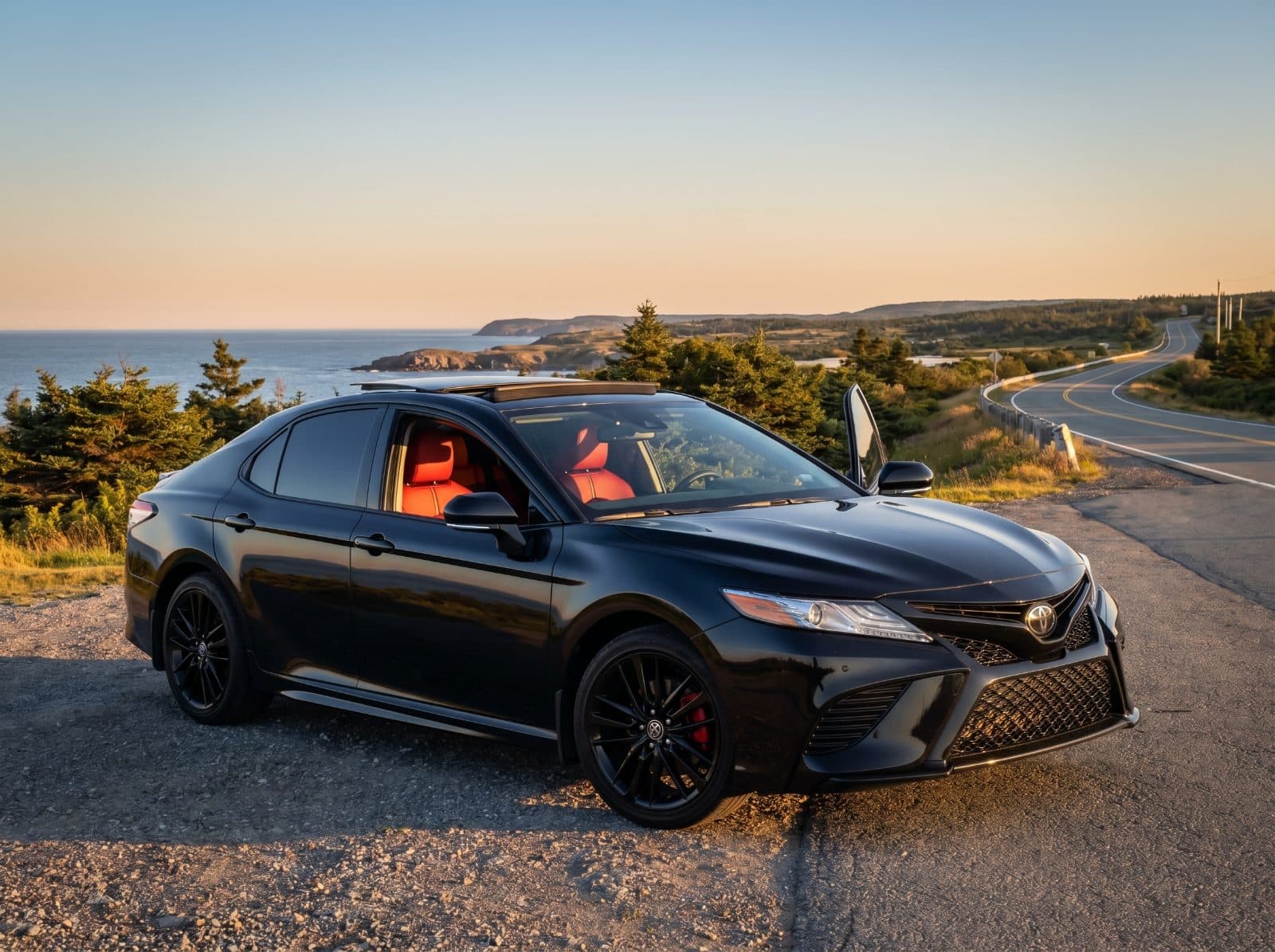 Black Toyota Camry XSE parked on a Nova Scotia coastal road at sunset